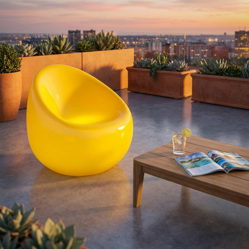 Poltrona luminosa gialla vibrante che brilla su una moderna terrazza panoramica al tramonto.