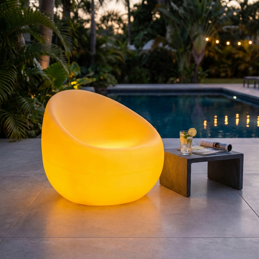 Poltrona contemporanea illuminata posizionata elegantemente a bordo di una lussuosa piscina all'imbrunire.