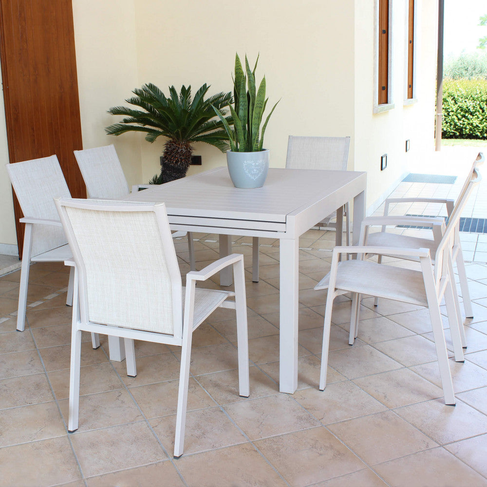 Set da pranzo outdoor con sei poltrone Maili impilabili attorno a un tavolo coordinato su una terrazza pavimentata.