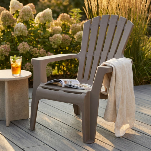 Poltrona da esterno Maryland color taupe con rivista e drink, circondata da ortensie illuminate dal sole.