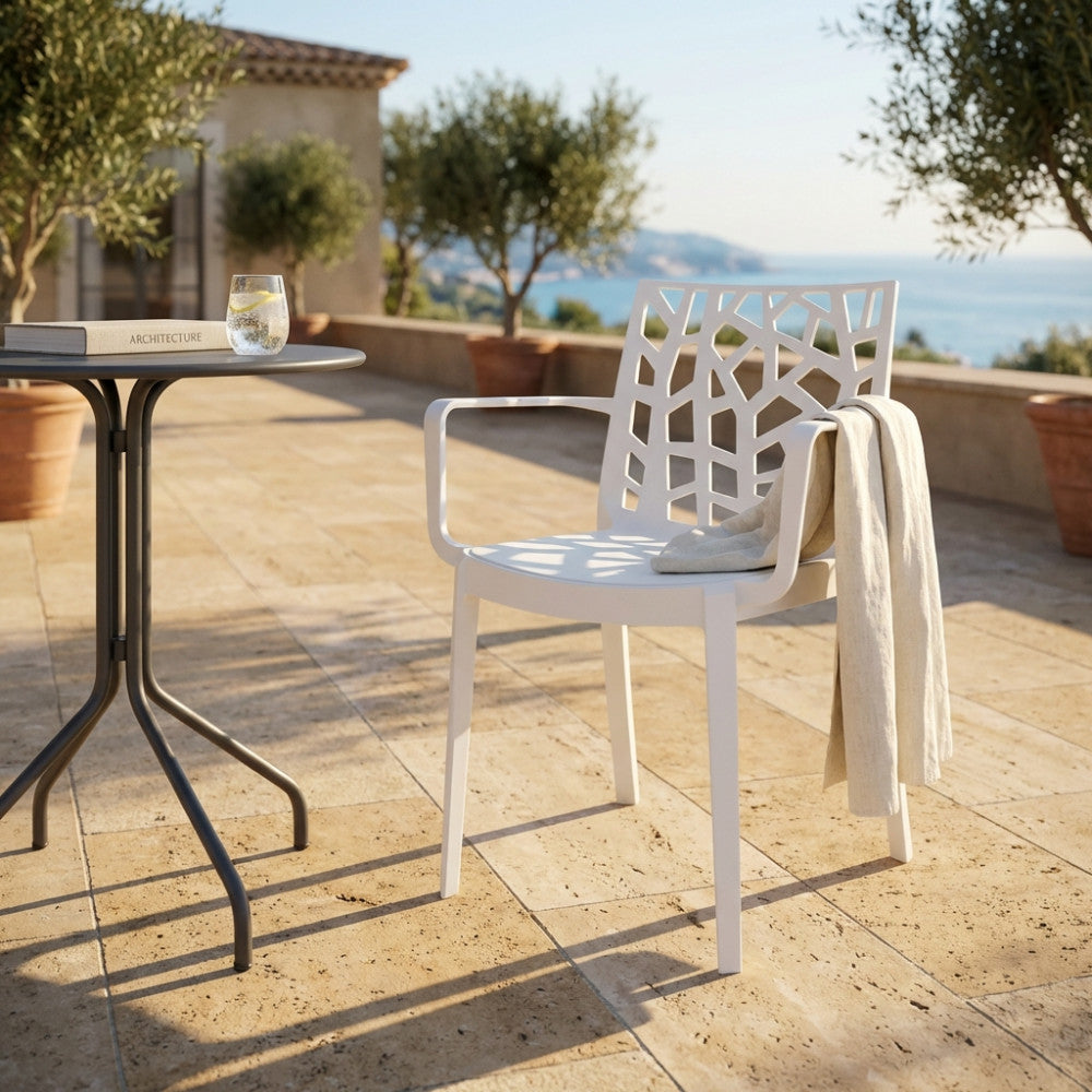 Poltrona Matrix in polipropilene bianco ambientata su una terrazza panoramica con vista mare e pavimentazione in pietra.
