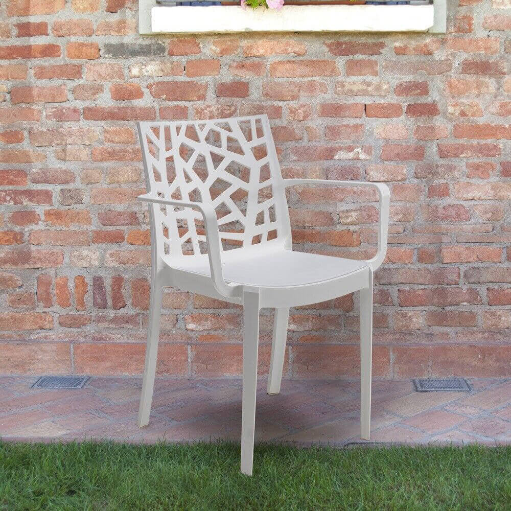 Poltrona Matrix bianca dal design moderno collocata all'aperto contro un muro rustico in mattoni a vista.