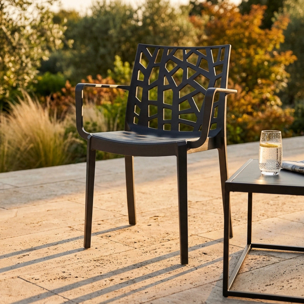 Poltrona Matrix in polipropilene nero ambientata su un patio in pietra illuminato dalla luce del tramonto.