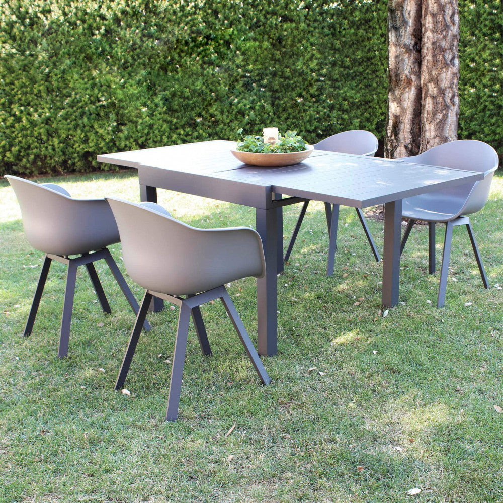 Composizione da giardino con tavolo allungabile e quattro poltrone Maui grigio antracite posizionate su un prato verde curato.