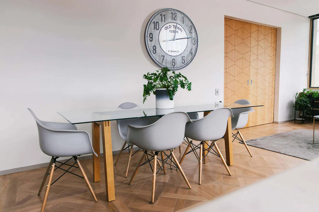 Poltrona Moritz grigia moderna con braccioli, seduta in ABS grigio e gambe in legno, ambientata in un soggiorno moderno con tavolo in vetro