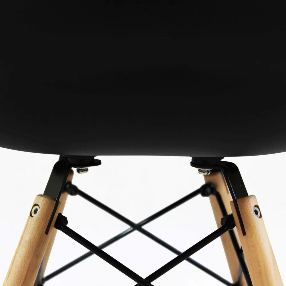 Poltrona Moritz nera con braccioli, seduta in plastica ABS nera e gambe in legno naturale e metallo, particolare incrocio delle gambe