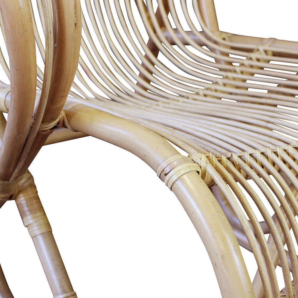 Poltrona Paloma a dondolo in fibra naturale con cuscini beige.