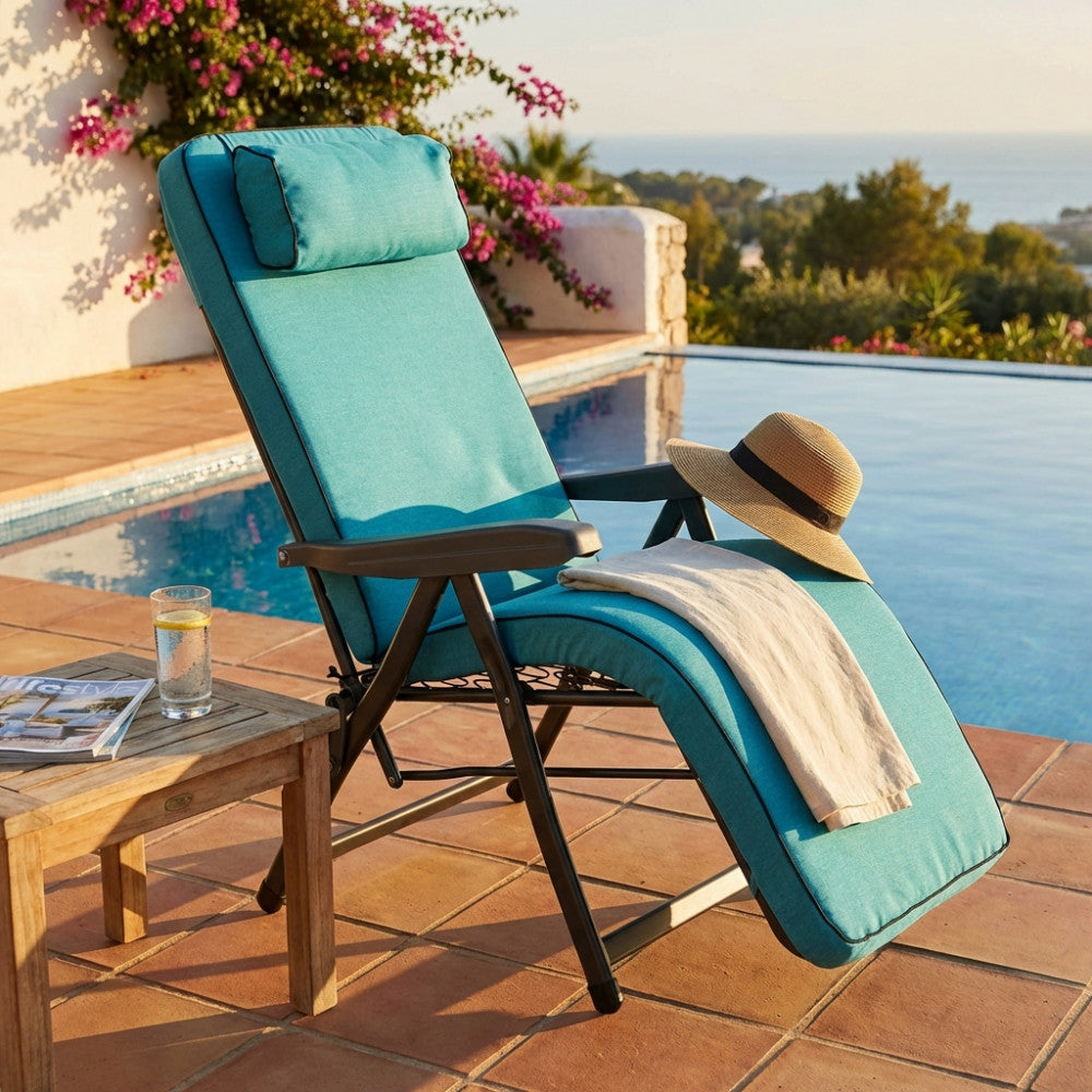 Poltrona relax Paradiso azzurra posizionata a bordo piscina con cappello di paglia e asciugamano.