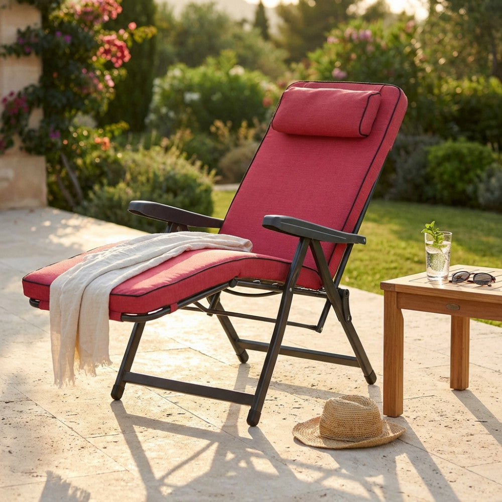 Poltrona relax Paradiso rossa in un giardino soleggiato con tavolino in legno.
