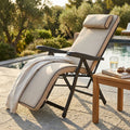 Poltrona relax Paradiso in tessuto beige e acciaio robusto, posizionata a bordo piscina accanto a un tavolino in legno.