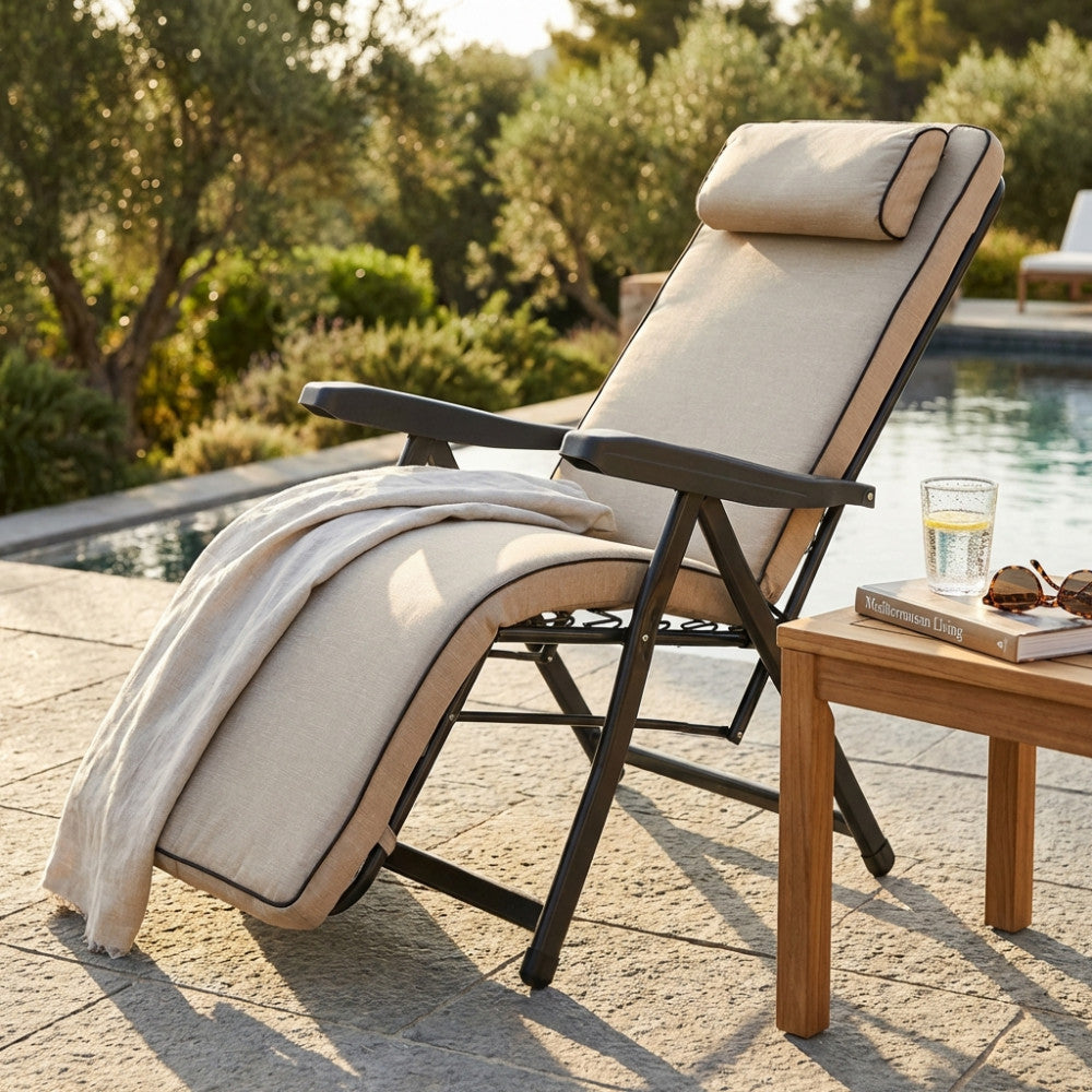Poltrona relax Paradiso in tessuto beige e acciaio robusto, posizionata a bordo piscina accanto a un tavolino in legno.