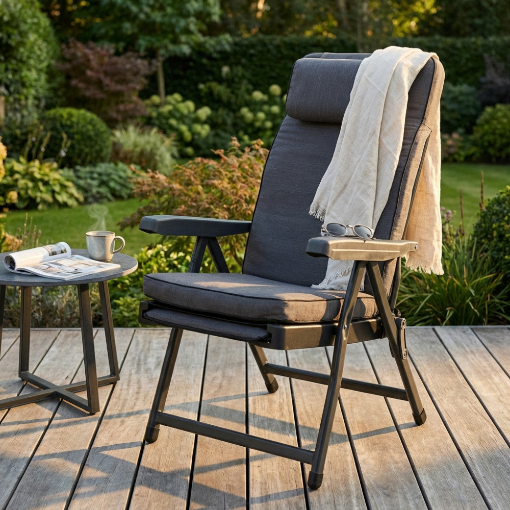 Poltrona relax Paradiso ambientata in un giardino di lusso su un deck in legno con tavolino.
