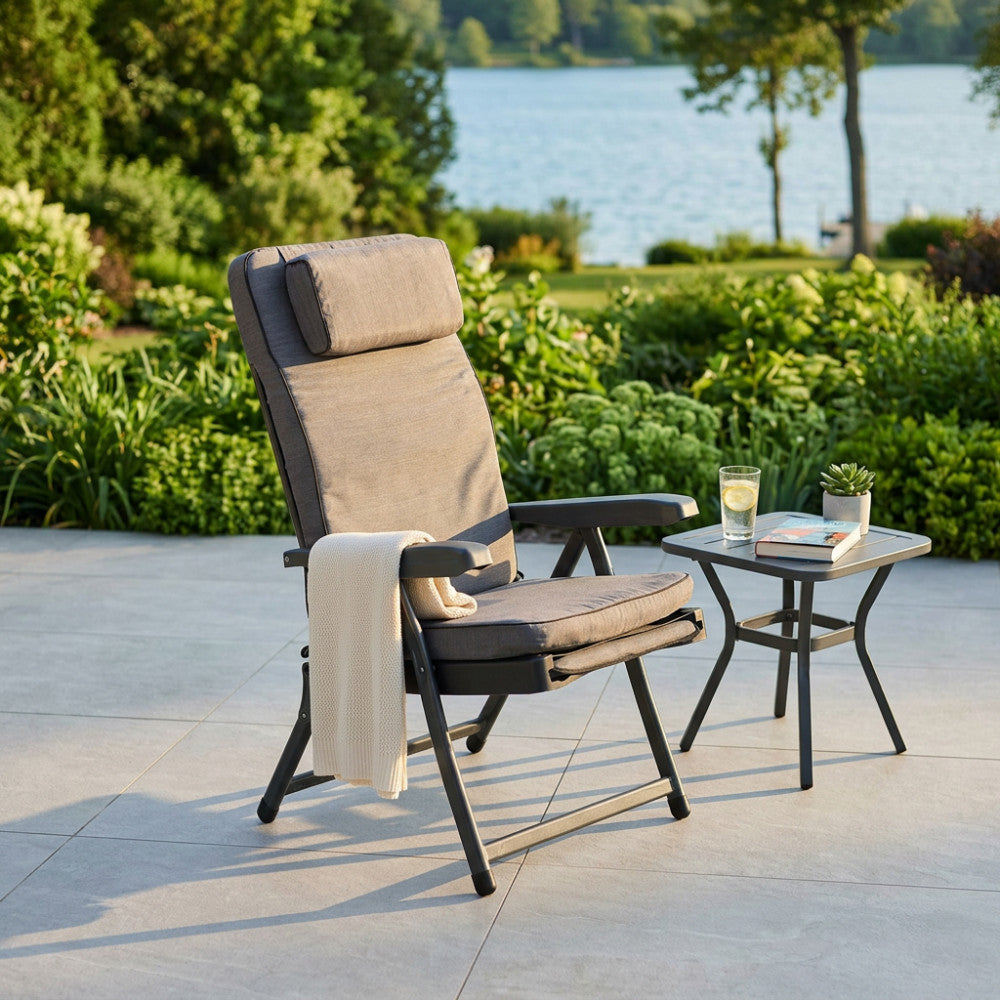 Poltrona relax grigia posizionata su una terrazza pavimentata con vista lago e accessori decorativi.