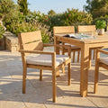 Poltrona Parker in teak con cuscino bianco, ambientata in un patio soleggiato accanto a un tavolo coordinato.