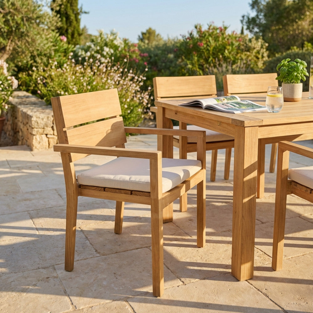 Poltrona Parker in teak con cuscino bianco, ambientata in un patio soleggiato accanto a un tavolo coordinato.
