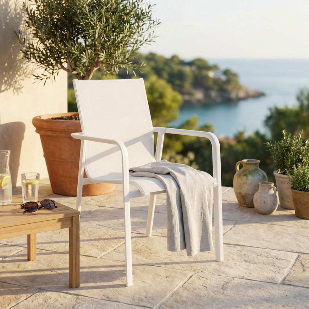 Poltrona Providence color gesso in alluminio posizionata su una terrazza in pietra con vista mare.