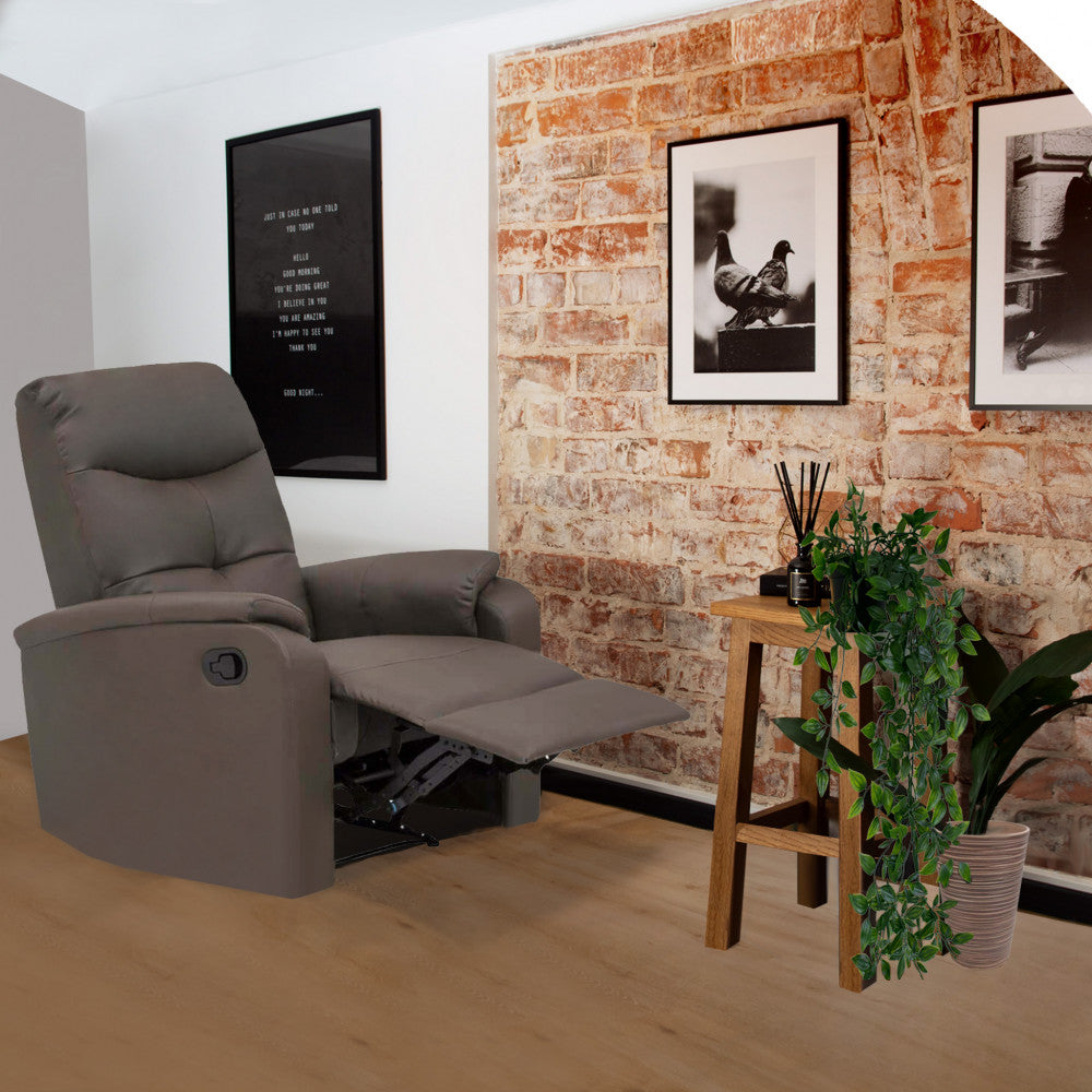 Poltrona relax reclinata in ecopelle marrone ambientata in un loft con parete in mattoni a vista e piante decorative.