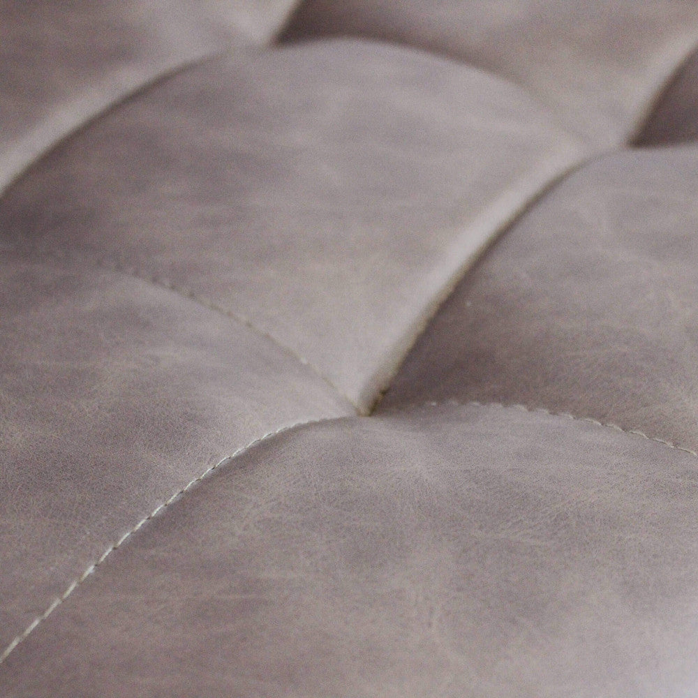 Primo piano sulle cuciture sartoriali e la texture trapuntata dell'ecopelle marrone della sedia Rosalyn.