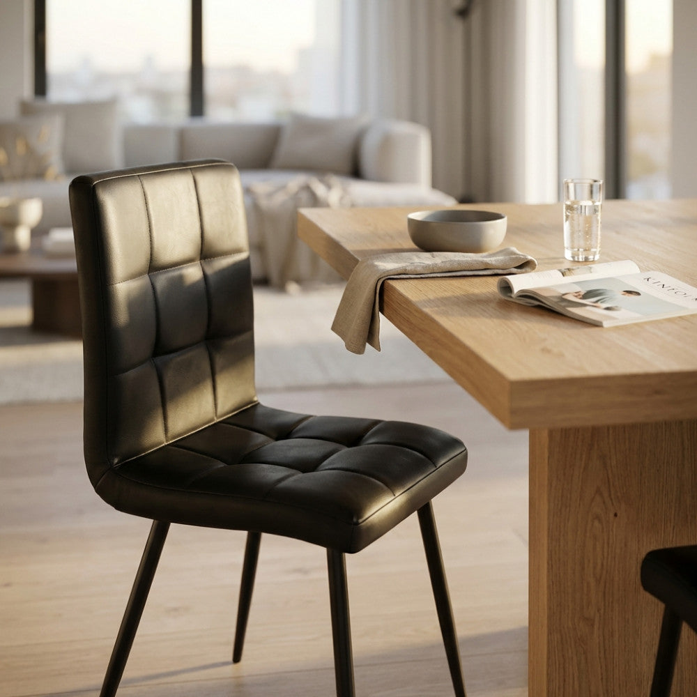 Poltrona Rosalyn in ecopelle nera ambientata in una sala da pranzo moderna e luminosa.