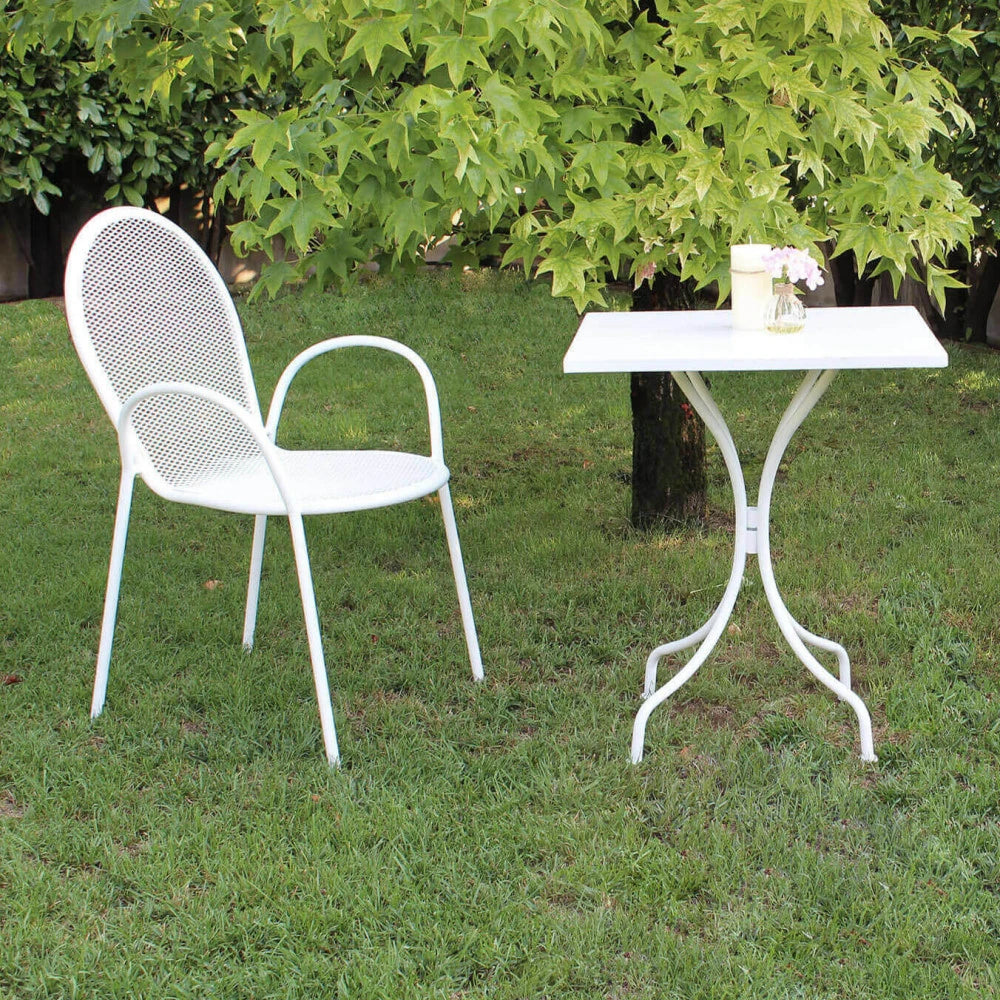 Poltrona Sheffield Bianca impilabile in metallo verniciato a polvere, design elegante e moderno per esterni, ambientata in giardino