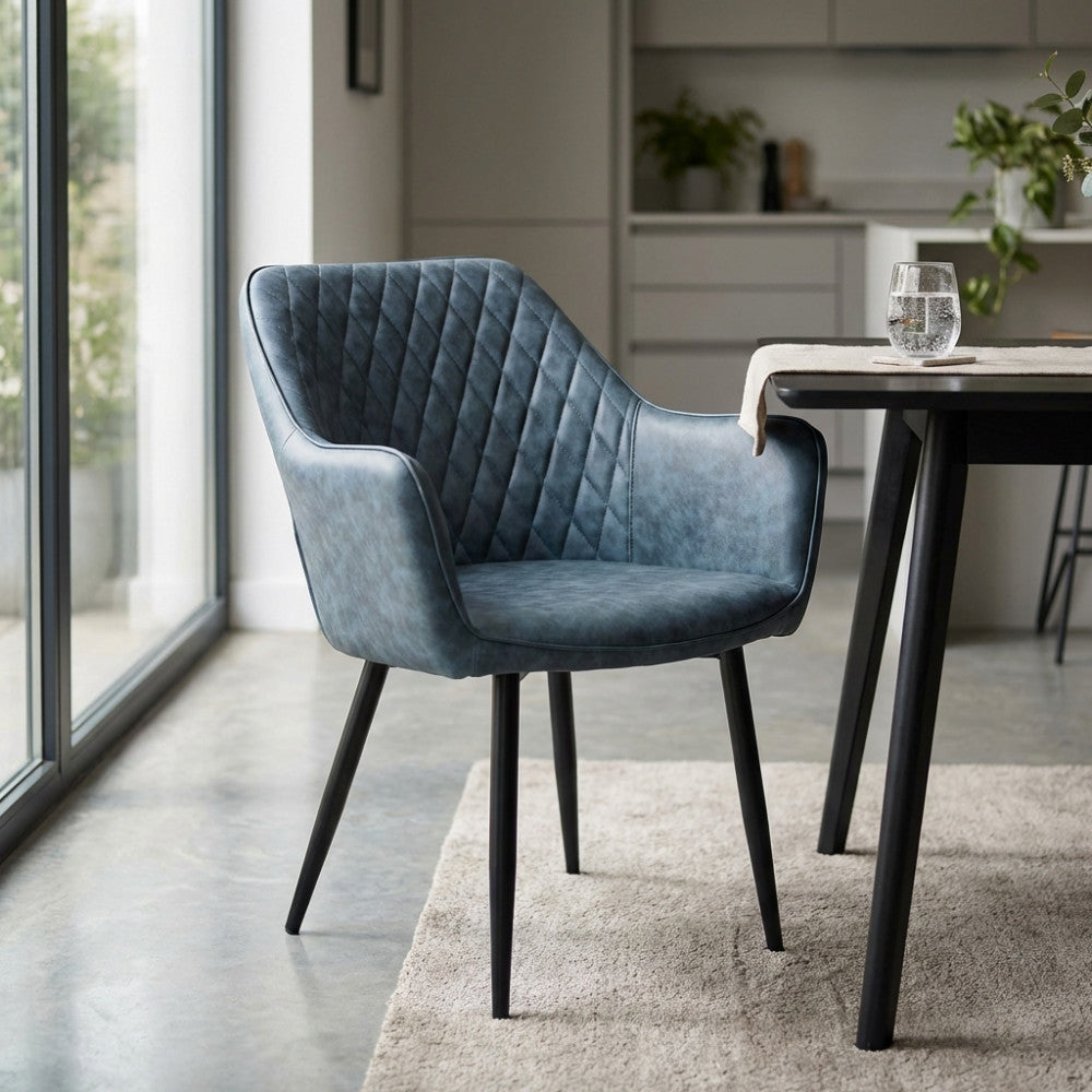 Poltrona Sindy in ecopelle blu inserita in una sala da pranzo moderna con pavimento in cemento spatolato e tavolo nero.