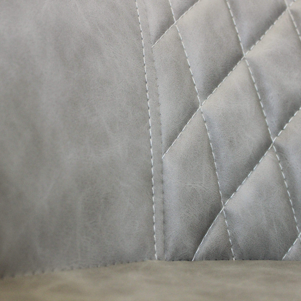 Dettaglio ravvicinato della texture trapuntata a rombi e delle cuciture sartoriali sull'ecopelle tortora della poltrona Sindy.