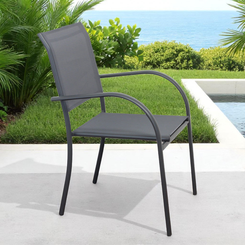 Poltrona Stamford inserita in un giardino lussureggiante con vista mare, evidenziando il design impilabile.