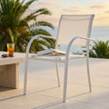 Poltrona Stamford in textilene bianco ambientata su una terrazza vista mare al tramonto.