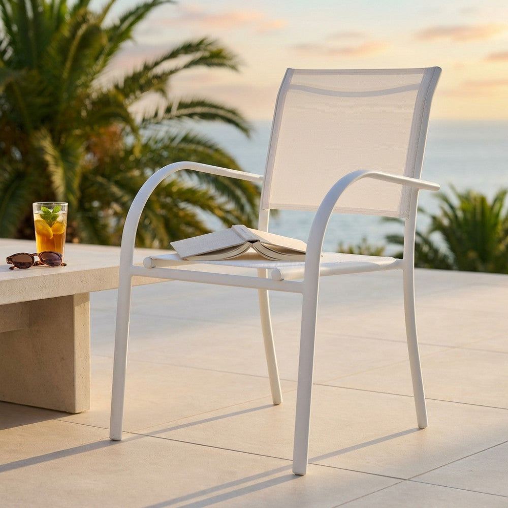 Poltrona Stamford in textilene bianco ambientata su una terrazza vista mare al tramonto.