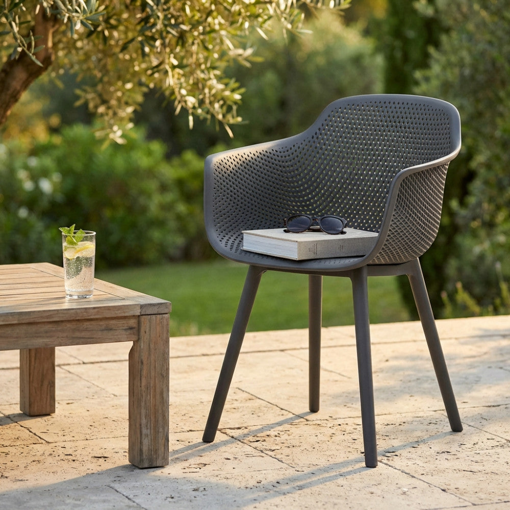 Poltrona Vannes taupe in un giardino lussureggiante, affiancata da un tavolino in legno massello.