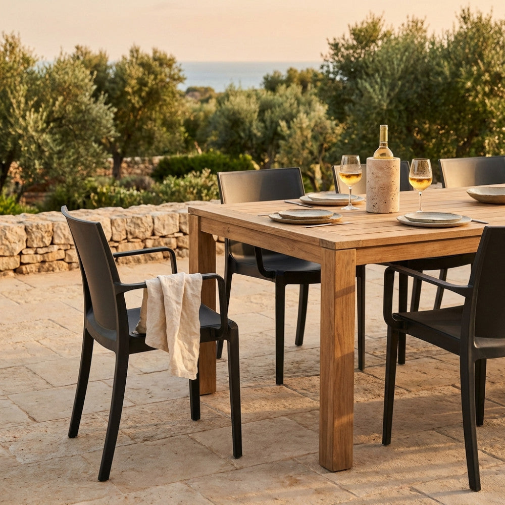 Set di poltrone Victoria antracite attorno a un tavolo in teak in un elegante giardino mediterraneo.