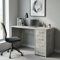 Scrivania Topaz in bilaminato effetto cemento ambientata in un home office moderno con sedia grigia e lampada nera.