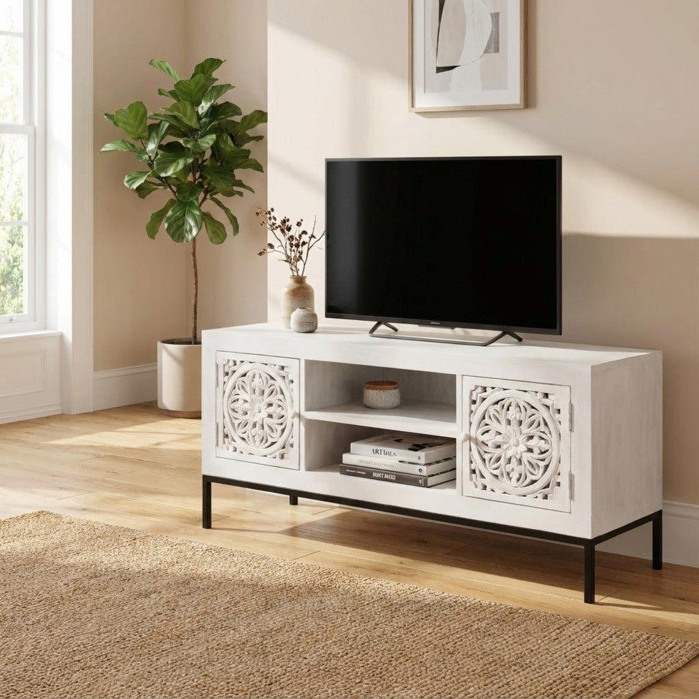 Porta TV Clifford in un ambiente domestico, decorato con libri d'arte e una pianta verde a foglia larga.