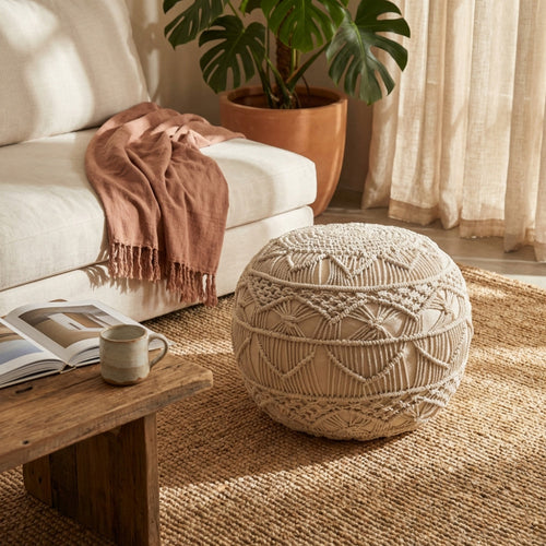 Dettaglio del Pouf Bodrum in cotone intrecciato a macramè, affiancato da un tavolino in legno massello rustico.