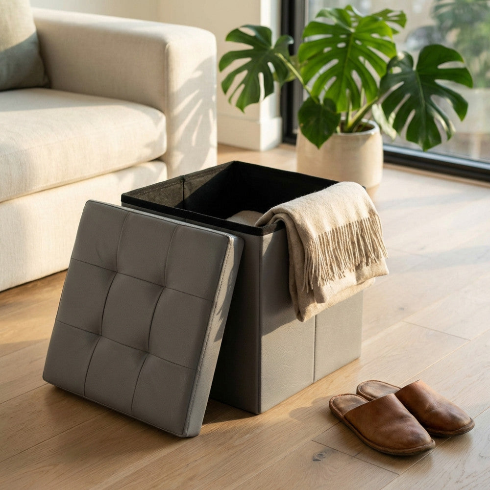Pouf contenitore quadrato in ecopelle grigio aperto in un salotto luminoso con divano bianco.