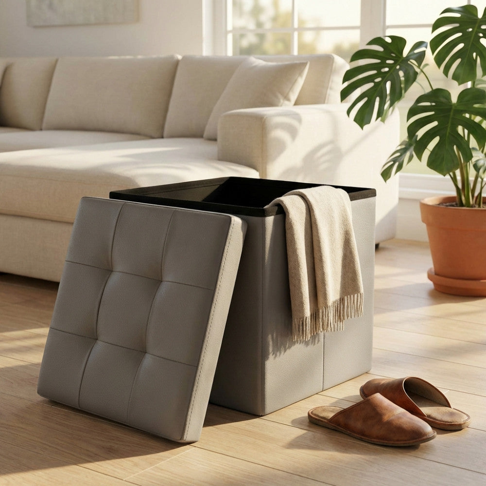 Pouf contenitore in ecopelle grigio con coperchio appoggiato a lato e coperta all'interno.