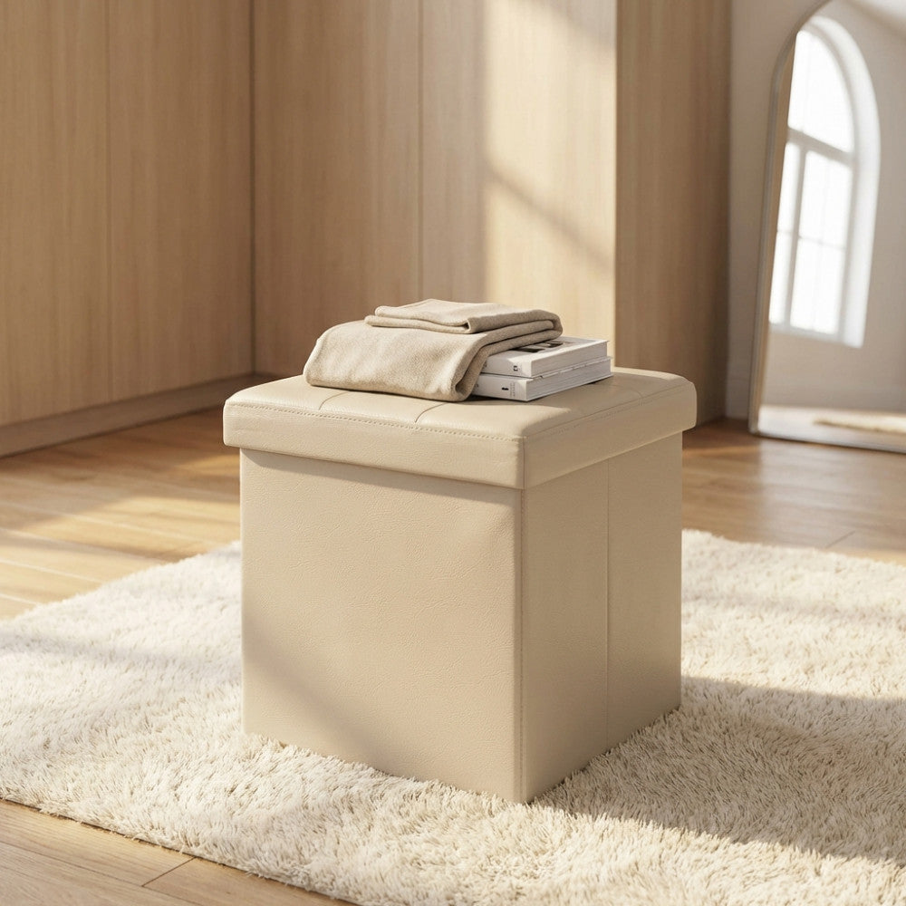 Pouf contenitore quadrato in ecopelle rosa pallido ambientato in una camera da letto luminosa con coperta e libri.