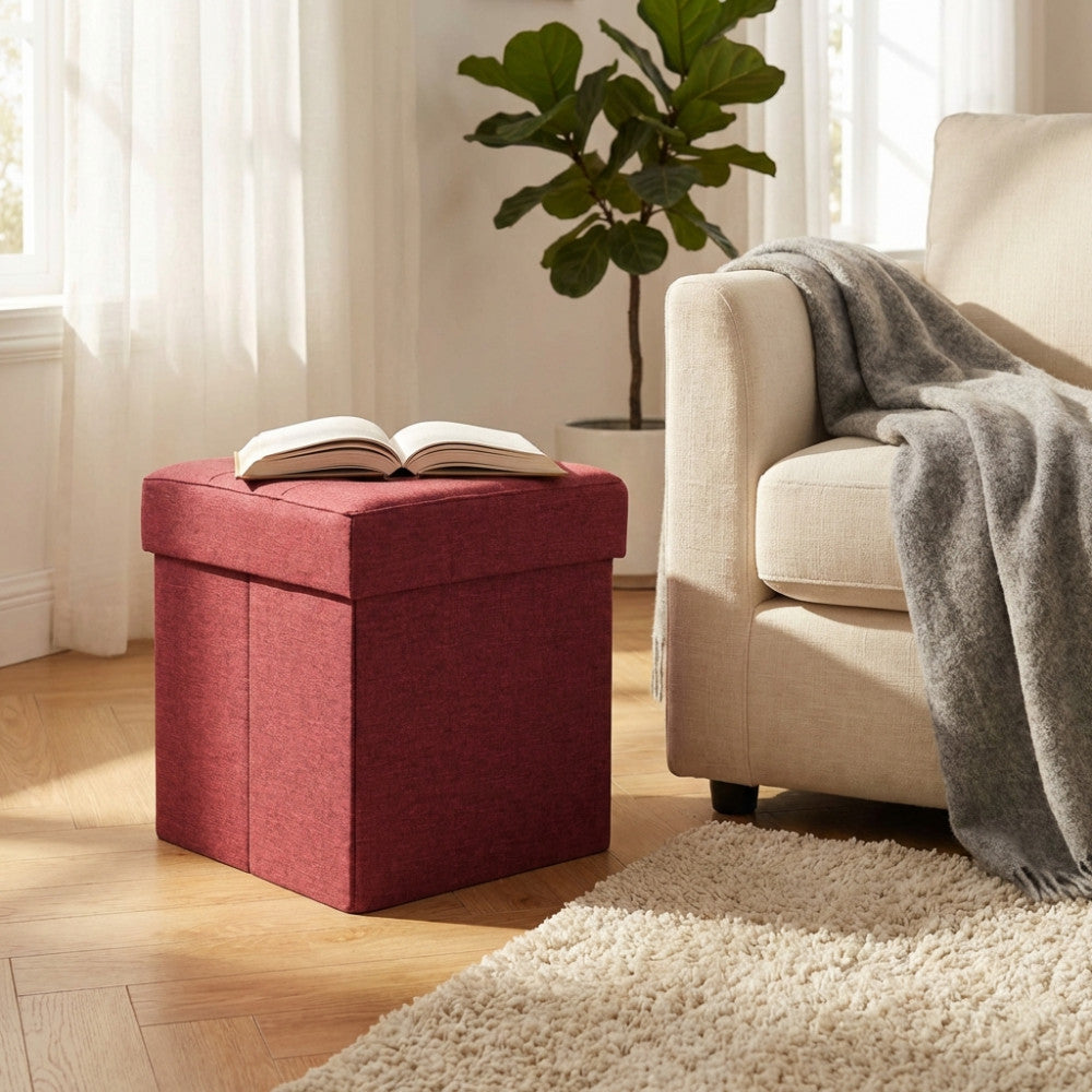Pouf contenitore bordeaux utilizzato come piano d'appoggio per un libro in un salotto dal design contemporaneo.