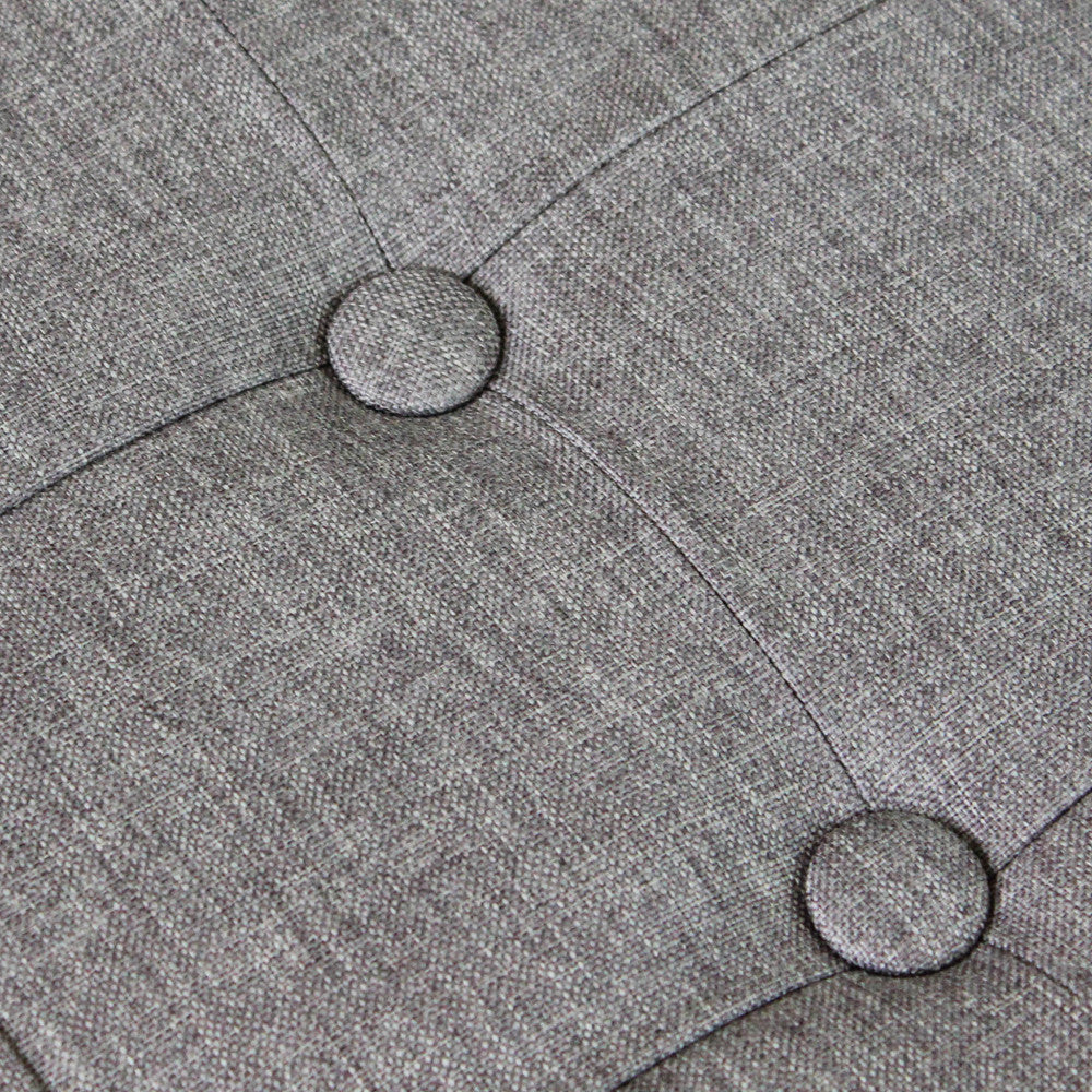 Dettaglio ravvicinato delle cuciture sartoriali e dei bottoni decorativi sulla seduta del pouf.