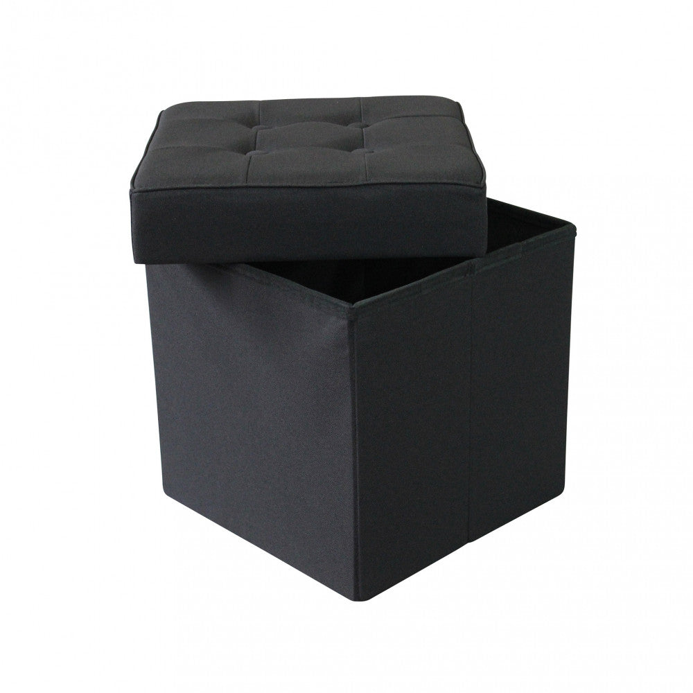 Pouf contenitore in tessuto nero con il coperchio capitonné appoggiato in modo asimmetrico.
