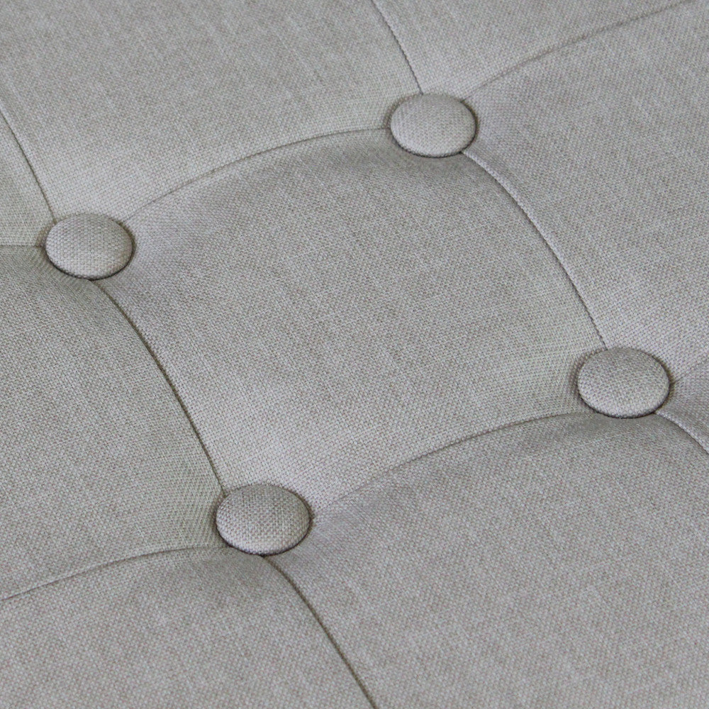 Macro sulla trama del tessuto tortora e sui bottoni decorativi della seduta del pouf.