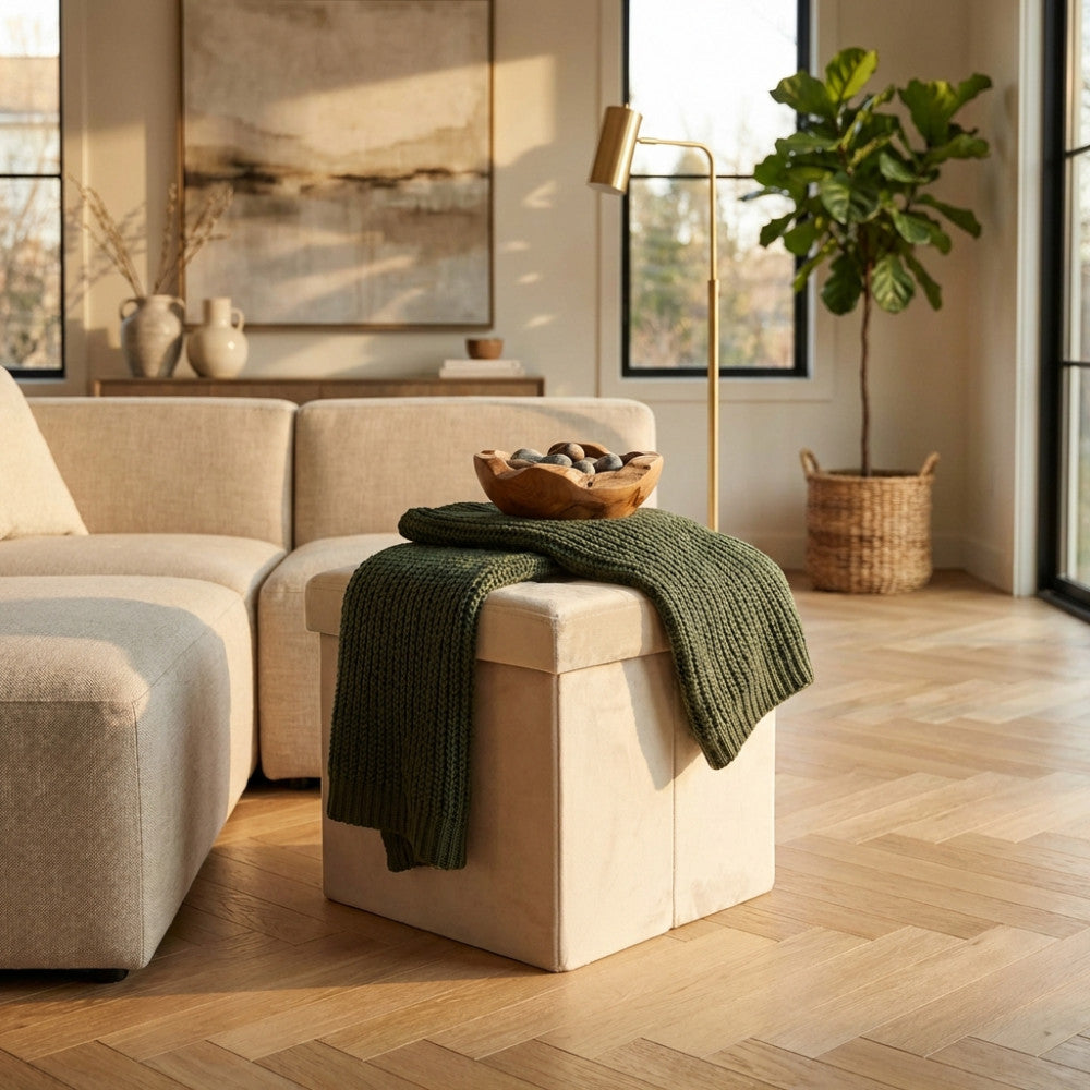 Pouf contenitore in velluto beige decorato con una coperta verde e una ciotola in legno in un ambiente elegante.