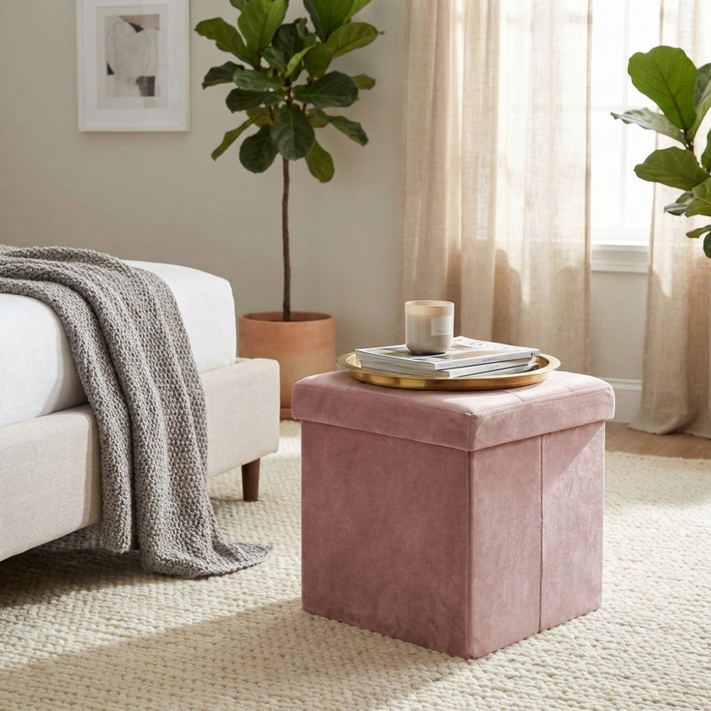 Pouf contenitore in velluto rosa posizionato in una camera da letto luminosa, utilizzato come comodino con un vassoio dorato.