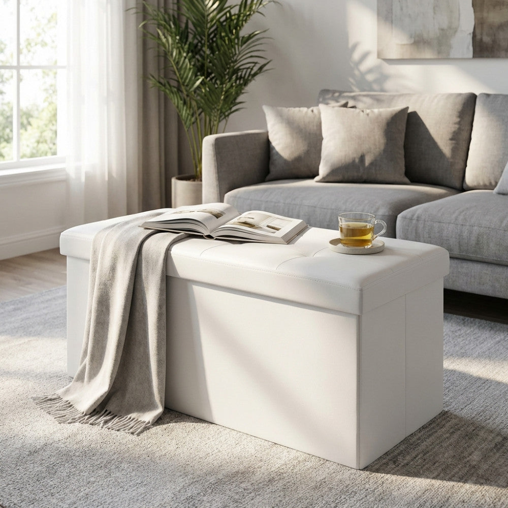 Pouf rettangolare bianco utilizzato come tavolino da salotto con libri e una tazza da tè.