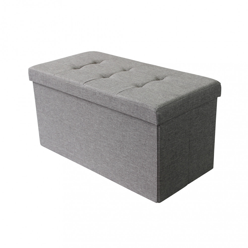 Dettaglio isolato del pouf contenitore rettangolare grigio su sfondo bianco, che evidenzia la seduta trapuntata.