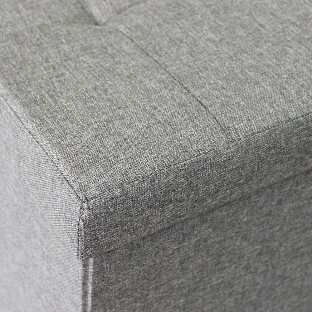 Dettaglio ravvicinato del tessuto grigio testurizzato e delle cuciture sartoriali sull'angolo del pouf.
