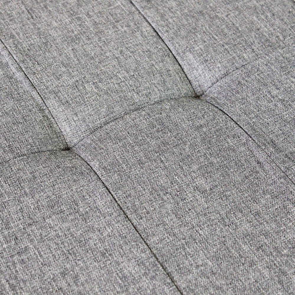 Macro fotografia della superficie trapuntata del pouf, che mostra la trama intrecciata del tessuto grigio.