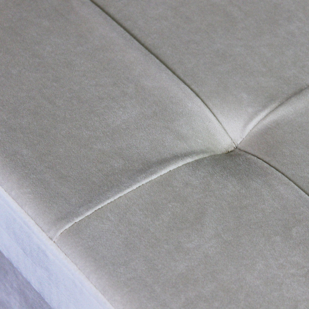 Dettaglio ravvicinato del tessuto in velluto beige e delle cuciture sartoriali del coperchio trapuntato.