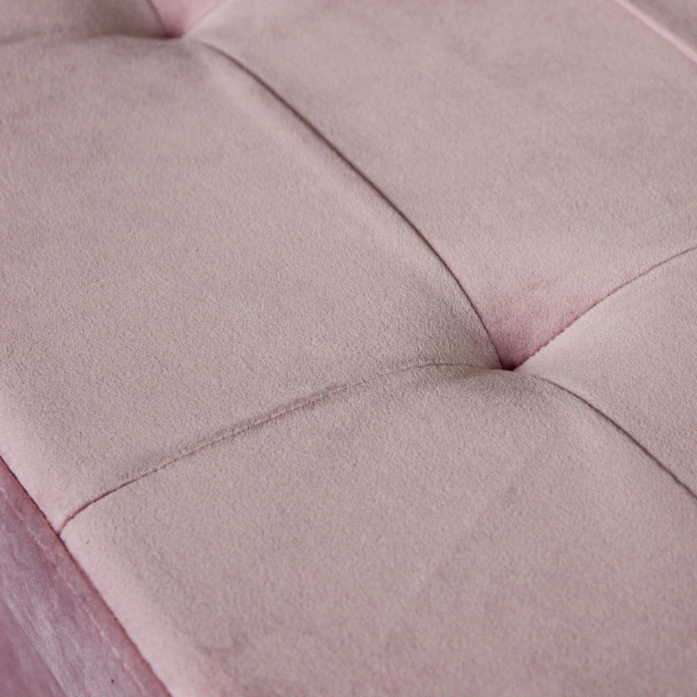Dettaglio ravvicinato della texture in velluto rosa e delle cuciture trapuntate sulla seduta del pouf.