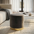 Pouf contenitore rotondo in velluto grigio scuro con base dorata, ambientato in un living luminoso accanto a un divano chiaro.